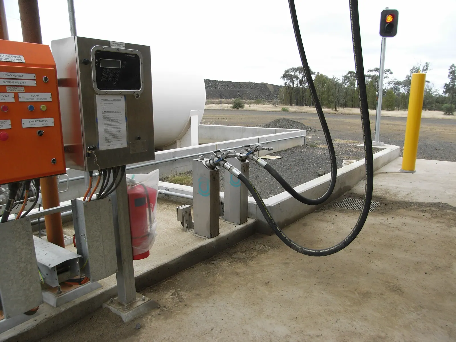 Ponto de abastecimento com painel de controle e mangueira, junto a um tanque